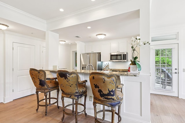 1010A Creekside, Greensboro, GA 30642 - kitchen featuring stainless steel appliances, a kitchen breakfast bar, light stone counters, light wood finished floors, and white cabinetry