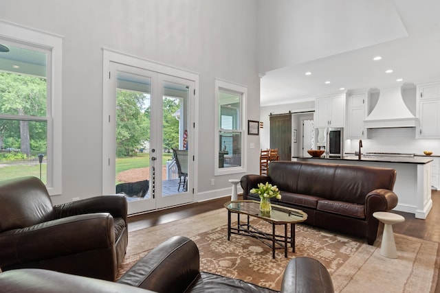 855 Jasper St, Madison, GA 30650 - living room with healthy amount of natural light, wood finished floors, a high ceiling, a barn door, and french doors