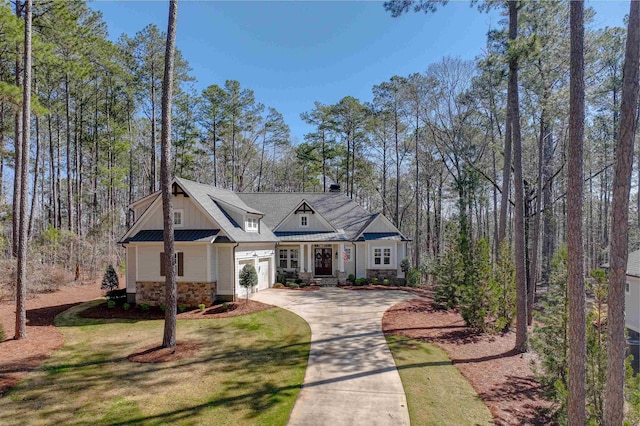 craftsman-style home with a front yard, driveway, a standing seam roof, stone siding, and metal roof