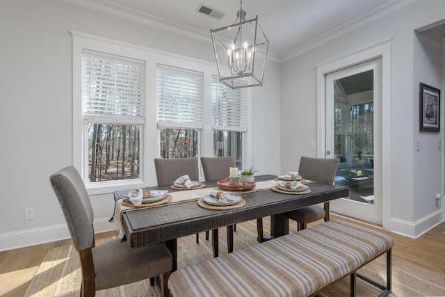 dining area with baseboards, visible vents, an inviting chandelier, ornamental molding, and light wood-style floors