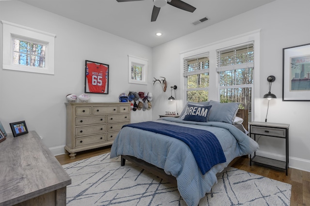 bedroom with multiple windows, wood finished floors, visible vents, and baseboards