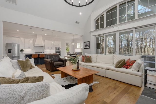 living area featuring an inviting chandelier, visible vents, and light wood finished floors