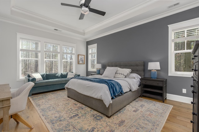 bedroom featuring a tray ceiling, visible vents, hardwood / wood-style floors, and ornamental molding