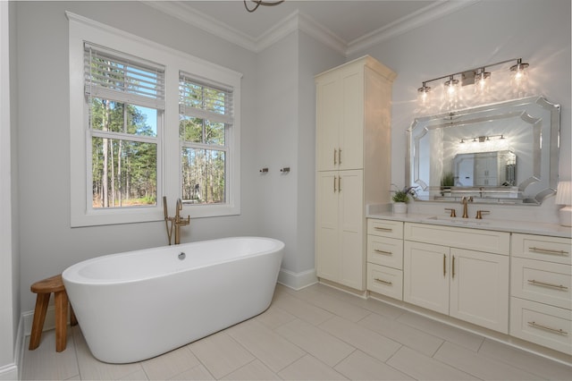 bathroom with tile patterned flooring, crown molding, baseboards, a freestanding bath, and vanity