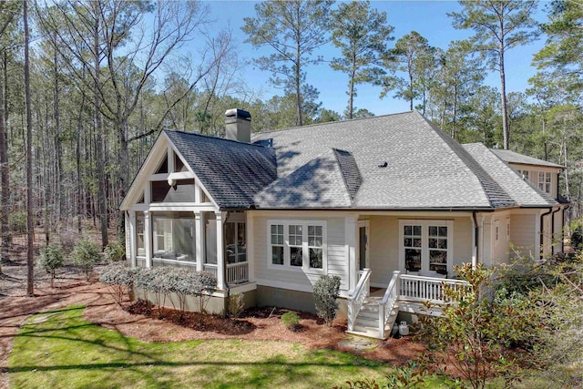 back of property featuring a shingled roof, french doors, a sunroom, and a chimney