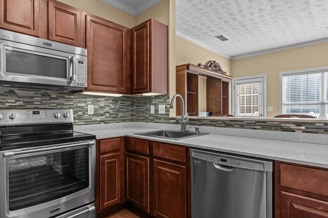 kitchen featuring sink, stainless steel appliances, tasteful backsplash, ornamental molding, and a textured ceiling