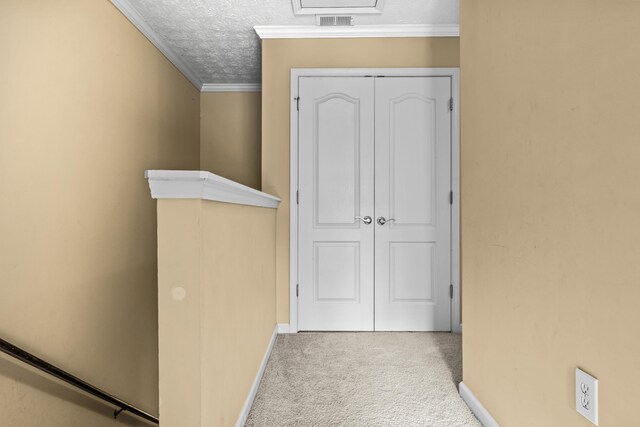 corridor with ornamental molding, carpet flooring, and a textured ceiling