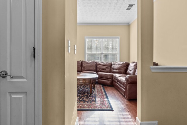 living room featuring hardwood / wood-style flooring, ornamental molding, and a textured ceiling