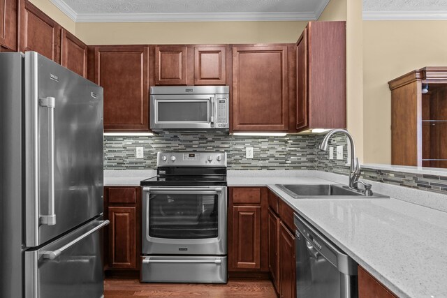 kitchen featuring sink, tasteful backsplash, ornamental molding, dark hardwood / wood-style floors, and stainless steel appliances