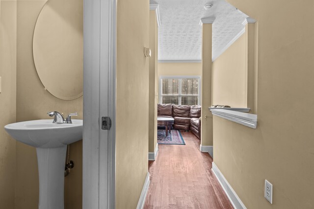 bathroom with sink, hardwood / wood-style flooring, ornamental molding, and a textured ceiling