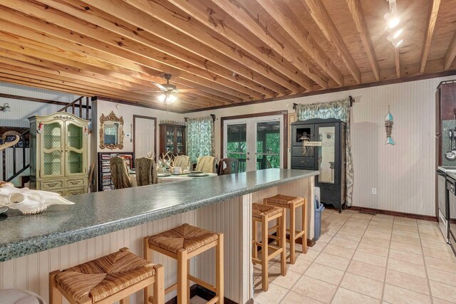 kitchen with beamed ceiling, light tile patterned floors, a kitchen bar, and french doors