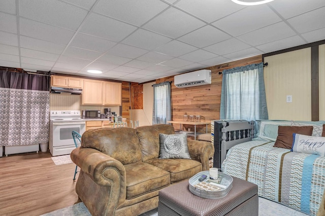 living room featuring a drop ceiling, light hardwood / wood-style floors, a wall mounted AC, and wood walls