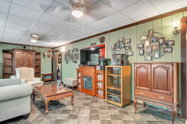 living room featuring crown molding, a paneled ceiling, and ceiling fan