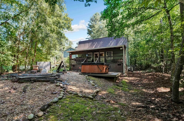 rear view of property with a hot tub and a deck