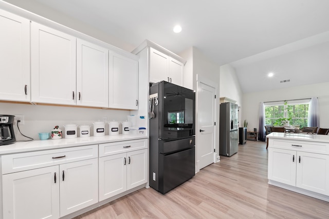165 Hunters Chase Ct, Eatonton, GA 31024 - kitchen with freestanding refrigerator, white cabinetry, light countertops, light wood-type flooring, and vaulted ceiling