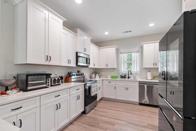 165 Hunters Chase Ct, Eatonton, GA 31024 - kitchen with appliances with stainless steel finishes, white cabinetry, light countertops, recessed lighting, and light wood-type flooring