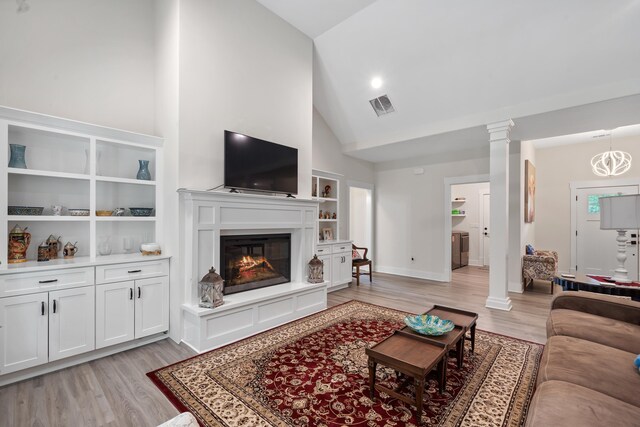 165 Hunters Chase Ct, Eatonton, GA 31024 - living room featuring ornate columns, light wood-type flooring, high vaulted ceiling, built in shelves, and a glass covered fireplace