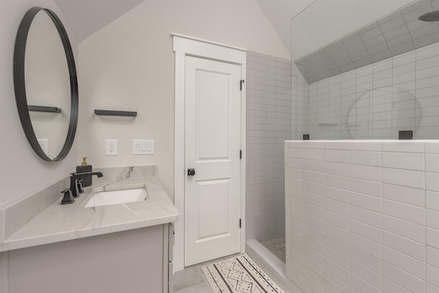 bathroom with vanity, vaulted ceiling, and tiled shower