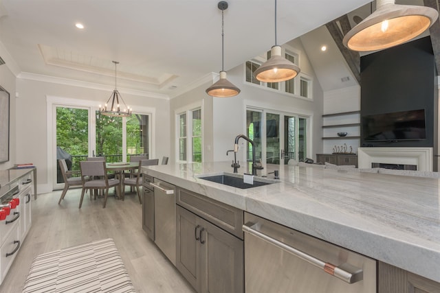 kitchen featuring sink, decorative light fixtures, light hardwood / wood-style flooring, dishwasher, and light stone countertops