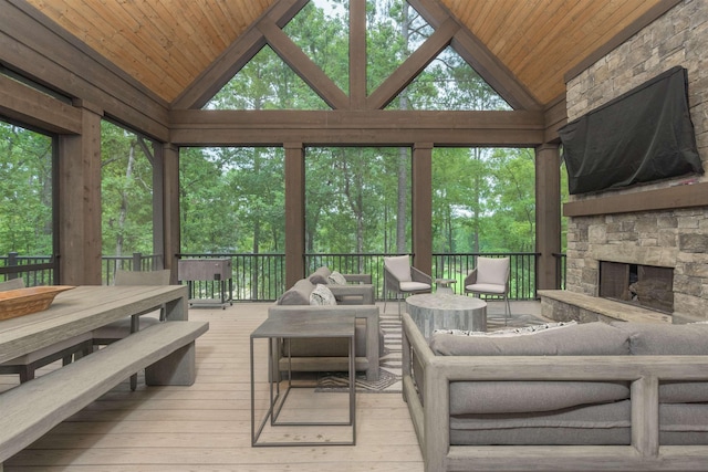 sunroom / solarium featuring lofted ceiling, wooden ceiling, and an outdoor stone fireplace