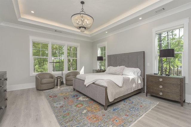 bedroom with a chandelier, a raised ceiling, and light hardwood / wood-style floors