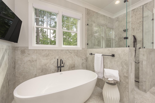 bathroom with shower with separate bathtub and tile walls