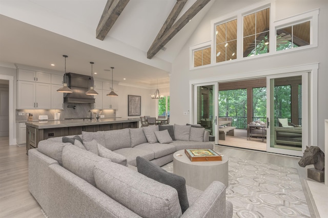 living room featuring beam ceiling, high vaulted ceiling, a chandelier, and light hardwood / wood-style floors