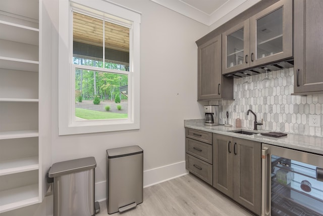 kitchen featuring light stone counters, beverage cooler, sink, and backsplash