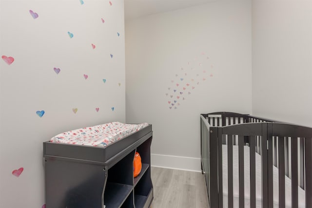 bedroom featuring a crib and light wood-type flooring