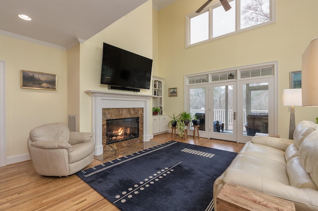 living room featuring hardwood / wood-style floors, a towering ceiling, a fireplace, and ornamental molding