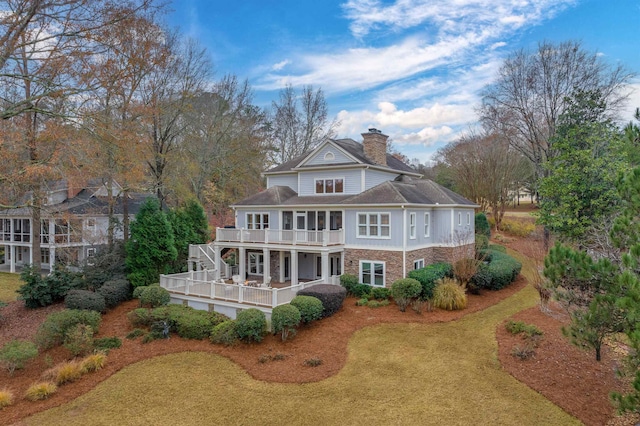 rear view of house with a wooden deck, a balcony, and a lawn