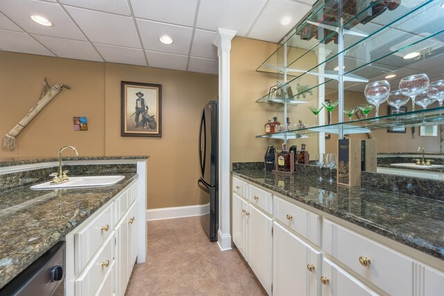 bar with white cabinetry, sink, and dark stone countertops