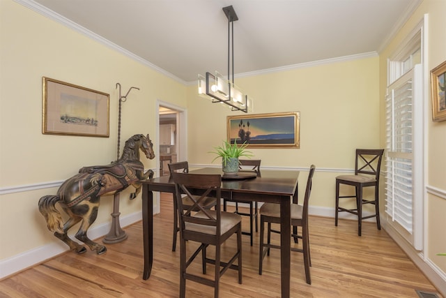 dining space with ornamental molding, a chandelier, and light wood-type flooring