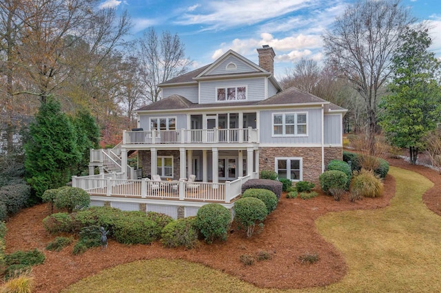 rear view of house featuring a lawn, a balcony, and a deck