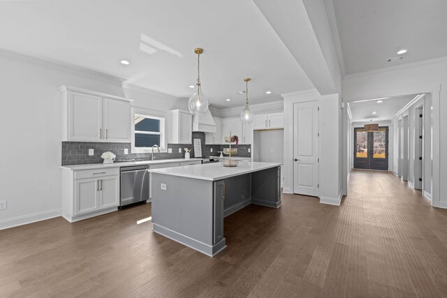 kitchen featuring a sink, stainless steel dishwasher, a center island, and white cabinetry