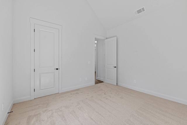 empty room with visible vents, lofted ceiling, baseboards, and carpet flooring