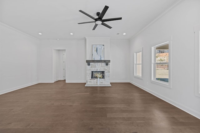 unfurnished living room with dark wood-type flooring, a fireplace, crown molding, baseboards, and ceiling fan