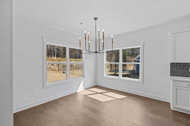 unfurnished dining area with visible vents, dark wood-type flooring, a notable chandelier, and ornamental molding