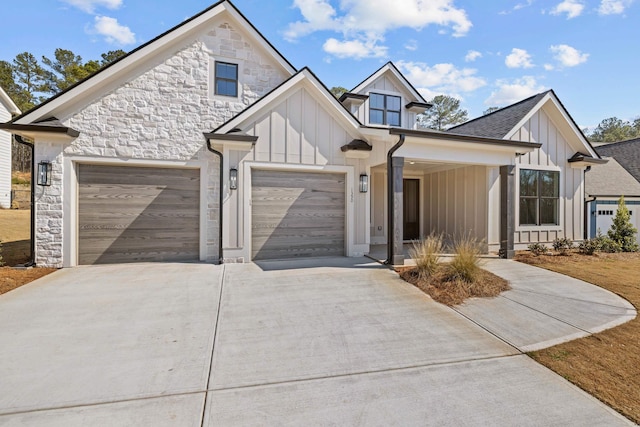 modern farmhouse style home with driveway, stone siding, board and batten siding, an attached garage, and a shingled roof