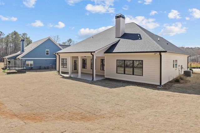 back of house with fence, roof with shingles, cooling unit, a chimney, and a patio area