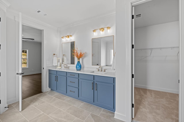 full bathroom with visible vents, double vanity, a sink, a spacious closet, and crown molding