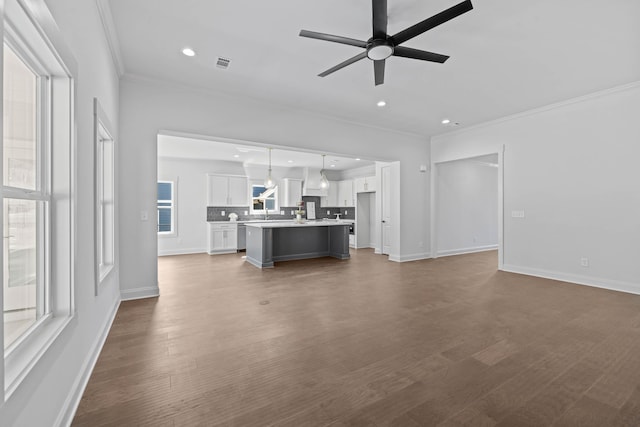 unfurnished living room featuring dark wood-style floors, visible vents, crown molding, and ceiling fan