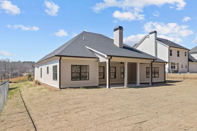 back of property featuring a shingled roof, a patio area, fence, and a chimney