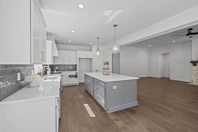 kitchen featuring dark wood-type flooring, pendant lighting, a sink, backsplash, and white cabinetry