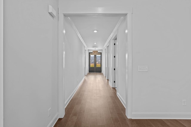 corridor with french doors, baseboards, dark wood finished floors, and ornamental molding