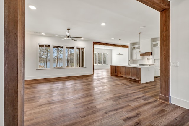 unfurnished living room with sink, dark hardwood / wood-style floors, and ceiling fan