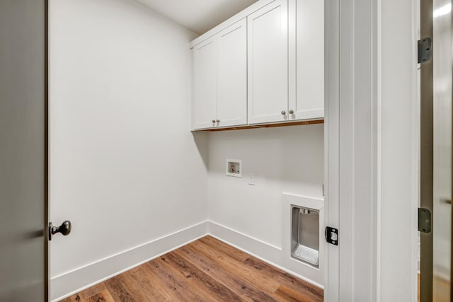 washroom with cabinets, washer hookup, and light hardwood / wood-style flooring