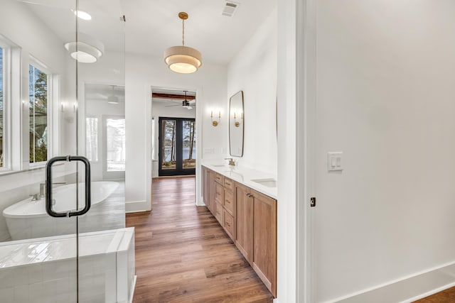 bathroom with hardwood / wood-style flooring, vanity, a bath, and french doors