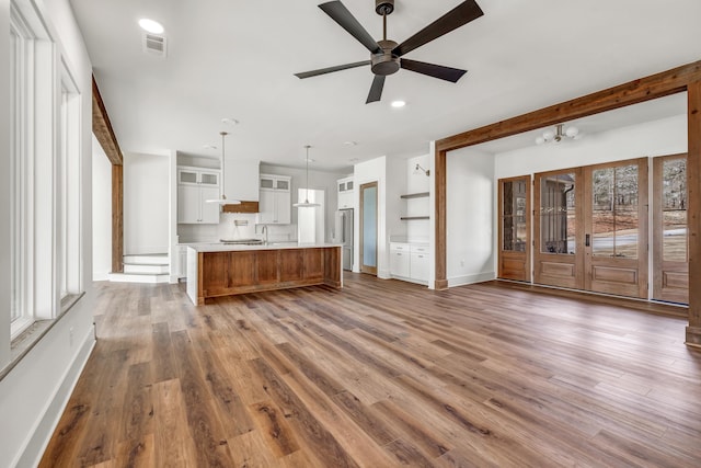 unfurnished living room with sink, hardwood / wood-style flooring, and ceiling fan