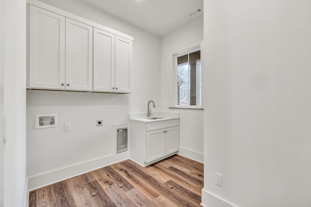 clothes washing area with sink, cabinets, washer hookup, light hardwood / wood-style floors, and electric dryer hookup